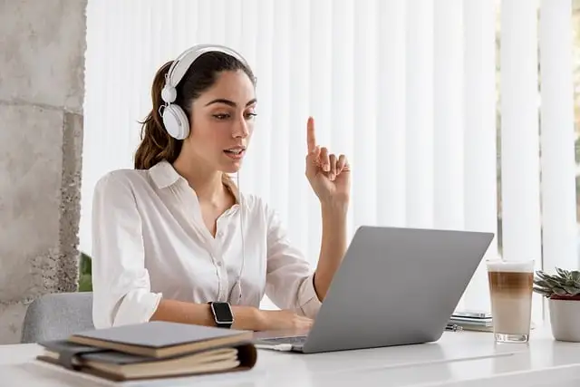 Femme suivant une formation d'anglais en ligne avec un casque audio, en préparation de la compréhension orale du TOEIC