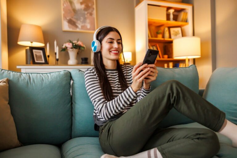 Jeune femme avec un casque suivant un cours de langue ludique sur son smartphone